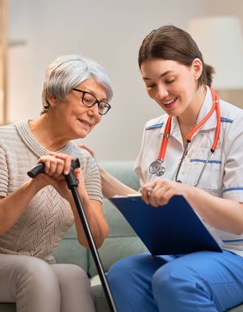 Elderly woman with cane looking at chart with nurse