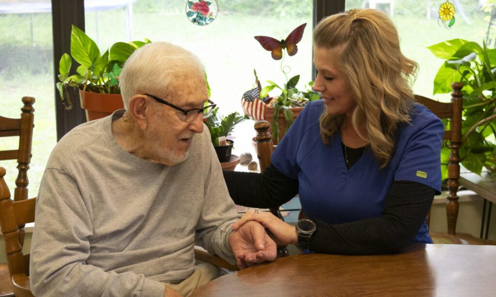 Nurse with elderly man at a table checking his pulse